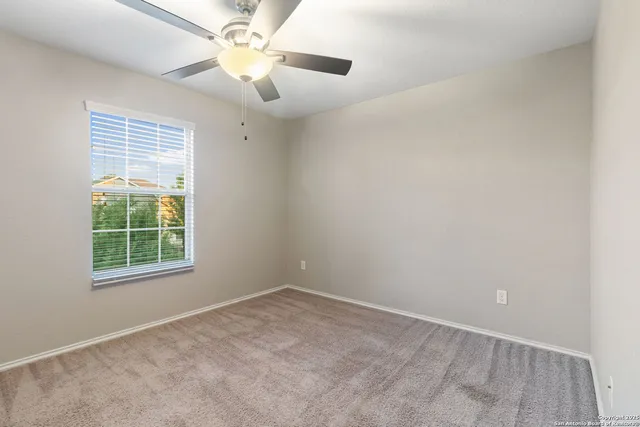 an empty room with a window and a fan