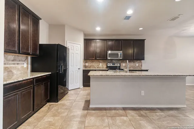 a kitchen with stainless steel appliances granite countertop a refrigerator and a sink