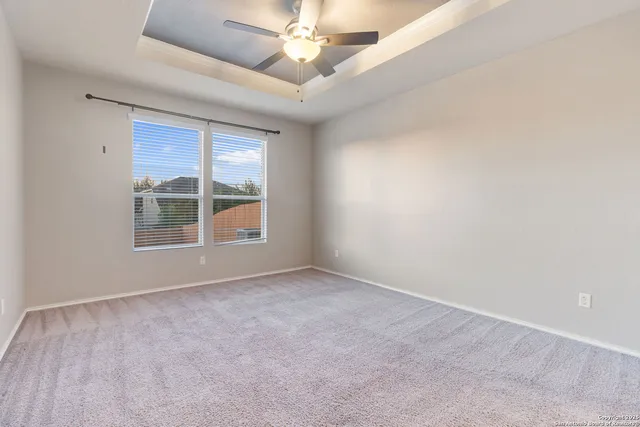 an empty room with windows and ceiling fan