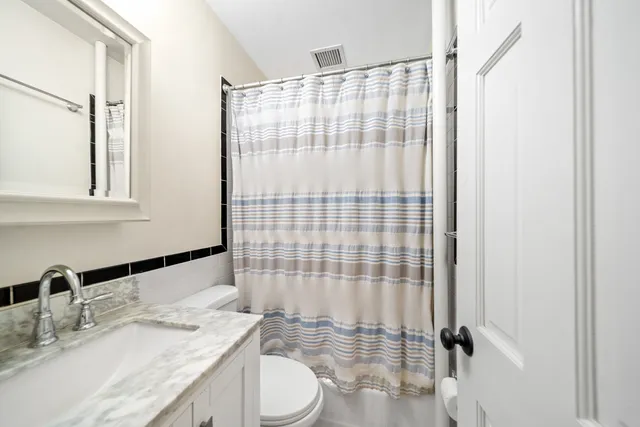 a bathroom with a granite countertop sink toilet a mirror and shower
