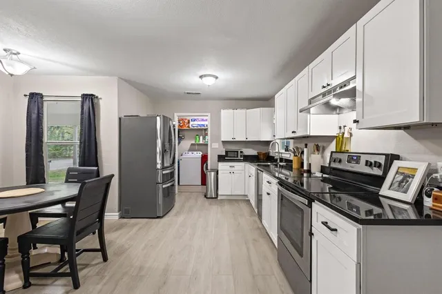 a kitchen with stainless steel appliances a refrigerator a stove a table and chairs