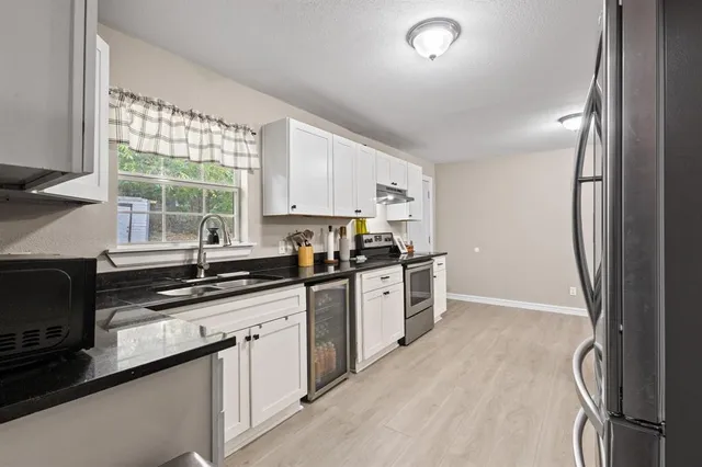 a kitchen with stainless steel appliances granite countertop a refrigerator a sink dishwasher a stove and white countertops with wooden floor