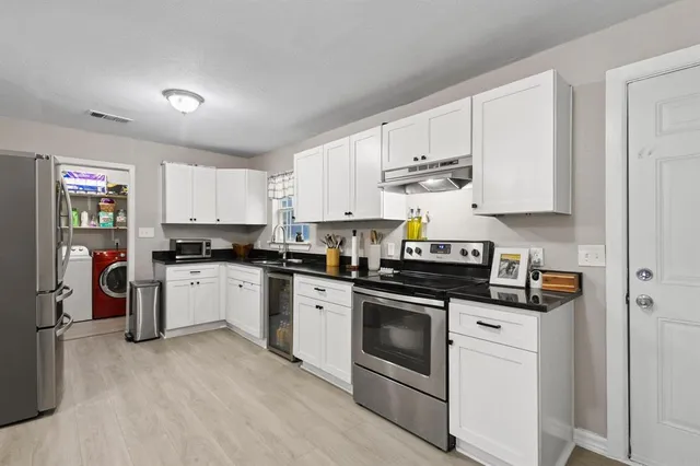 a kitchen with stainless steel appliances granite countertop a stove and white cabinets