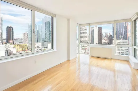 a view of a big room with wooden floor and windows