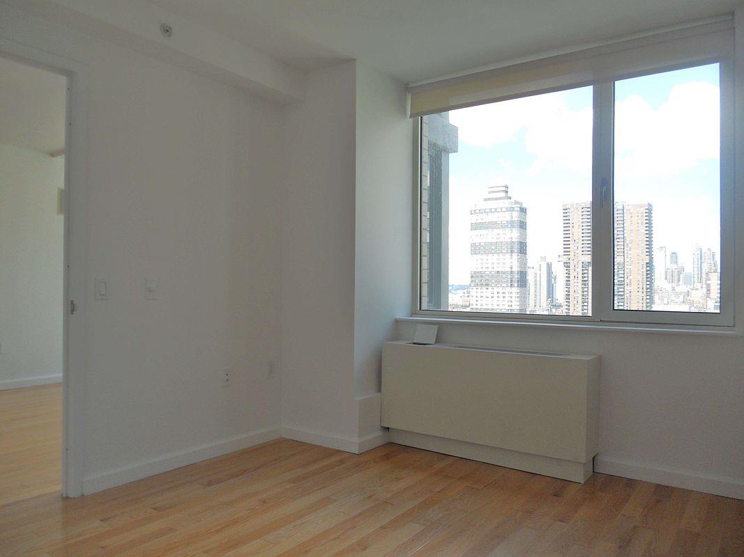 350 West 37th Street, Unit 16C Manhattan, NY 10018 - Photo 6 of 9 a view of an empty room with wooden floor and a window