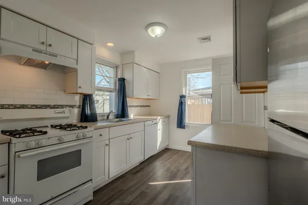 a kitchen with granite countertop a sink a stove and cabinets