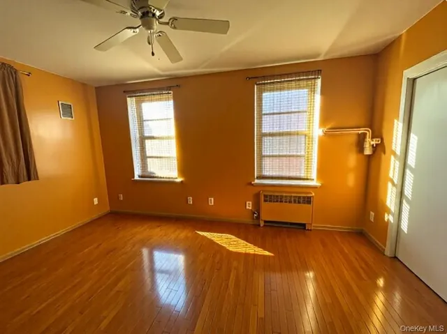 a view of an empty room with a window and wooden floor
