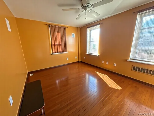 a view of an empty room with a window and wooden floor