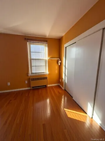 an empty room with wooden floor closet and windows