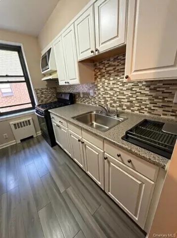a kitchen with granite countertop a stove a sink and wooden floor