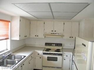5499 Rattlesnake Hammock Road, Unit 204 Naples, FL 34113 - Photo 2 of 7 a kitchen with white cabinets and white appliances