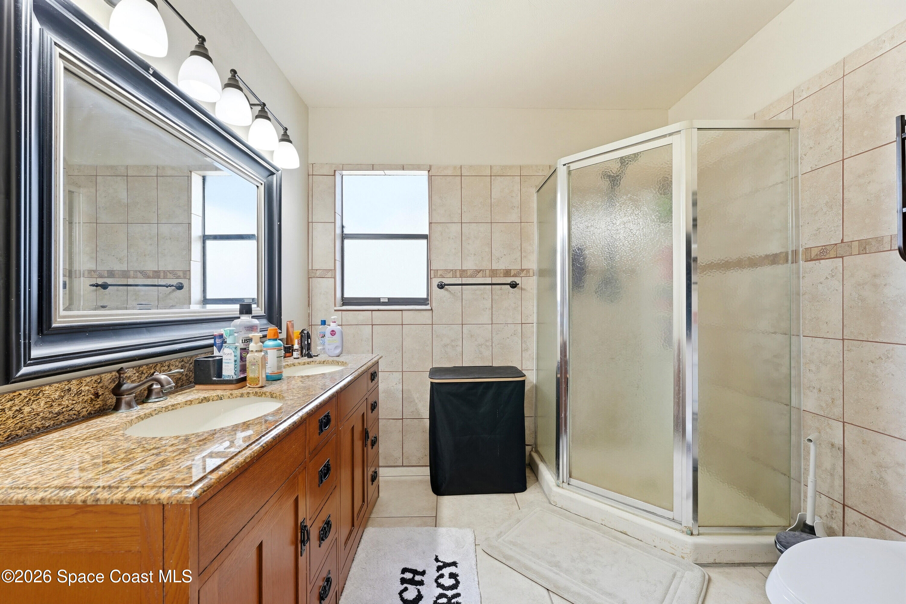 830 Garvey Road Palm Bay, FL 32908 - Photo 21 of 48 a bathroom with a granite countertop sink a mirror and a shower