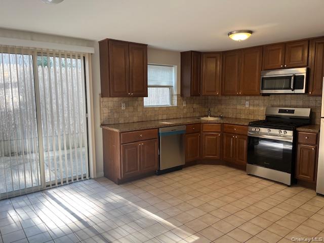 92 Harbor Road Port Washington, NY 11050 - Photo 4 of 15 Kitchen with appliances with stainless steel finishes, tasteful backsplash, light tile patterned flooring, and dark stone countertops