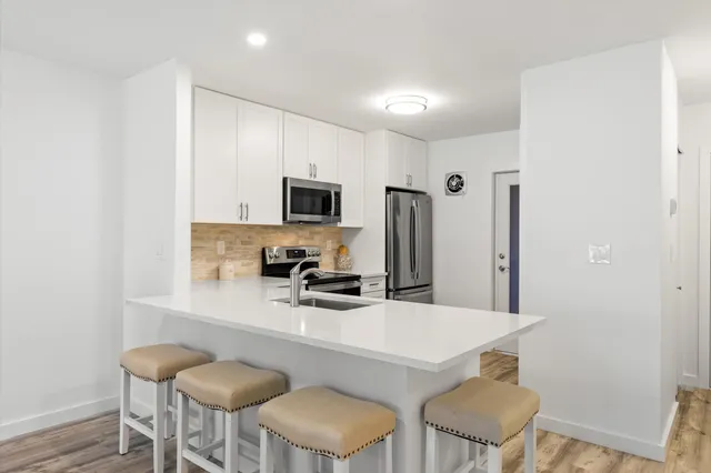 a kitchen with white cabinets and chairs