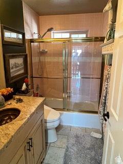 983 Grindelwald Lane, Unit O4 Midway, UT 84049 - Photo 11 of 14 Bathroom featuring a vanity with an integrated sink, a toilet, and a combination tub and shower with a gold-toned framed glass enclosure