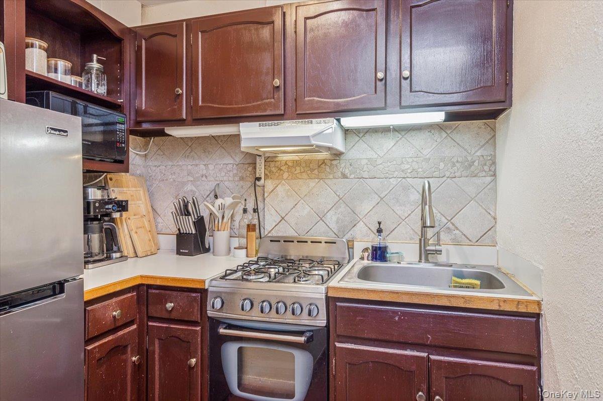600 Pelham Road, Unit A2D New Rochelle, NY 10805 - Photo 5 of 19 Kitchen with decorative backsplash, gas range oven, light countertops, freestanding refrigerator, and a textured wall