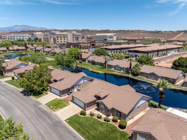 805 South River Road, Unit 70 St. George, UT 84790 - Photo 35 of 38 Aerial perspective highlighting a residential community with an artificial waterway featuring a fountain, surrounded by single-story homes with tiled roofs
