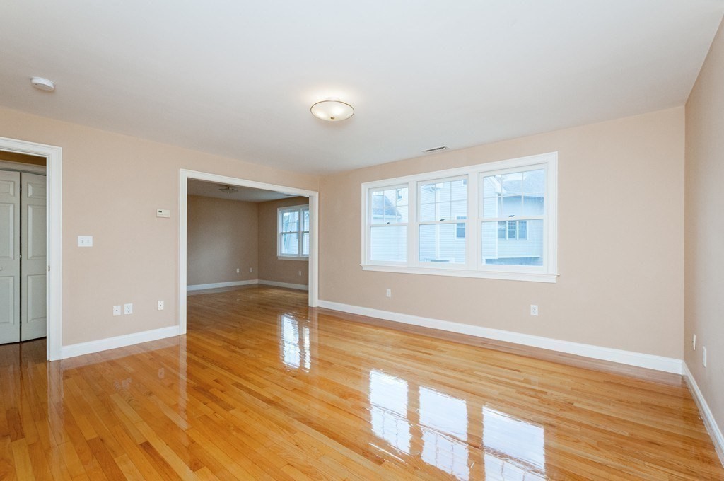 232 Pearl Street, Unit 232 Newton, MA 02458 - Photo 13 of 27 wooden floor in an empty room with a window