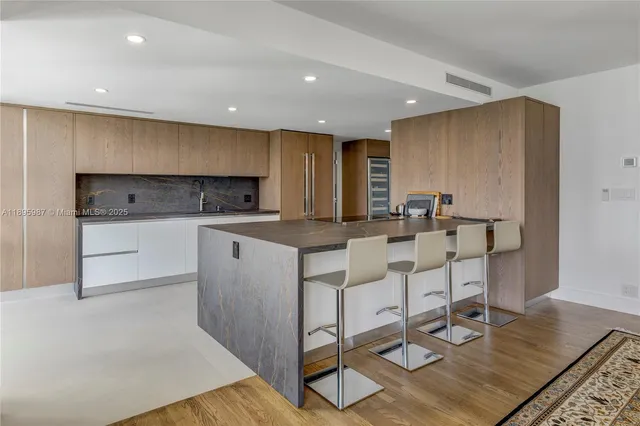 a kitchen with white cabinets a sink a stove a dining table and chairs