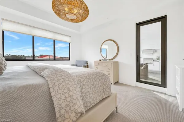 a bedroom with a bed and a large mirror next to a window