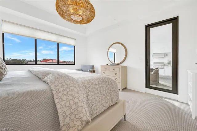 a bedroom with a bed and a large mirror next to a window