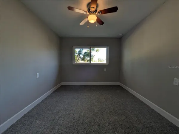 an empty room with a window and a fan