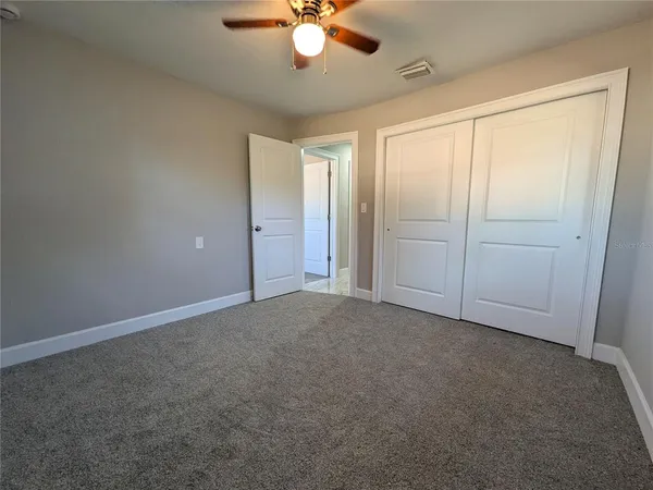 an empty room with closet and fan