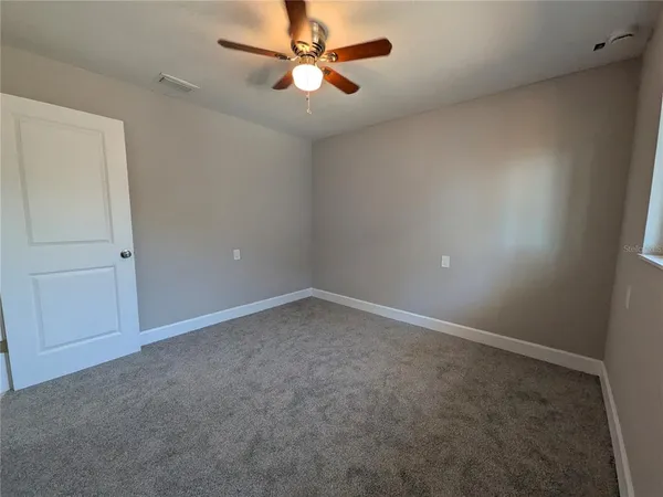 an empty room with a fan and a ceiling fan