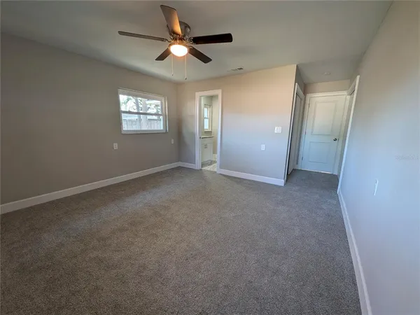 an empty room with windows and fan