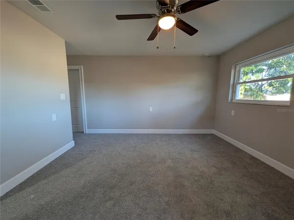 an empty room with a window and a fan