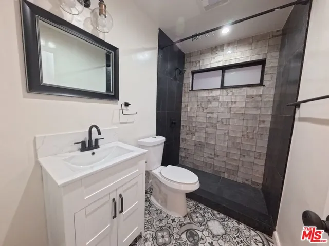 a bathroom with a sink a toilet a mirror and shower