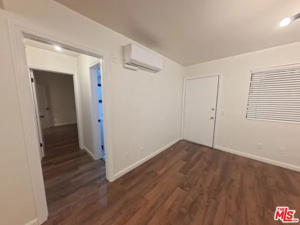 an empty room with wooden floor and a hallway