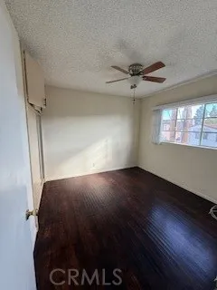 a view of a livingroom with a fireplace a ceiling fan and wooden floor