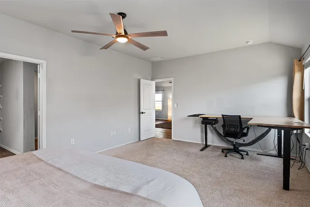 a spacious bedroom with a bed and a ceiling fan
