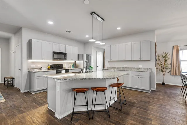 a kitchen with white cabinets stainless steel appliances and wooden floor