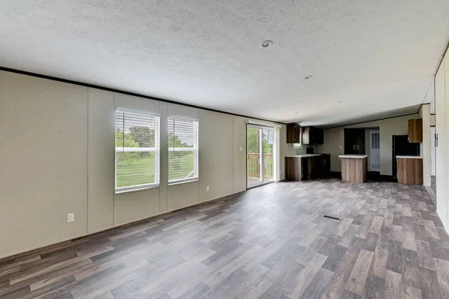 a view of an empty room with a window and a kitchen