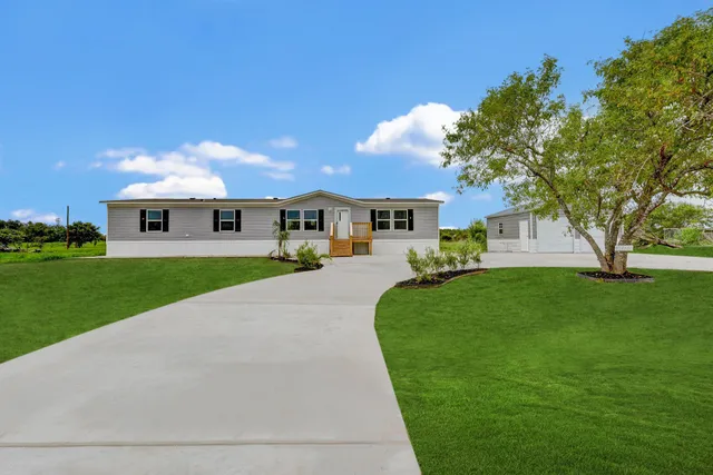 a front view of a house with a yard and trees