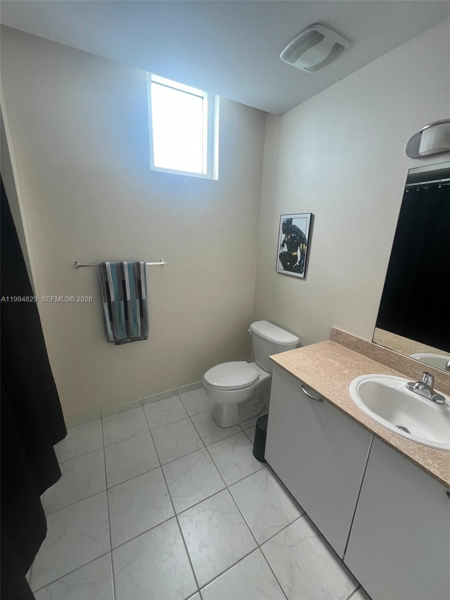 3180 Southwest 22nd Terrace, Unit 607 Miami, FL 33145 - Photo 12 of 18 a bathroom with a granite countertop sink a toilet and a mirror