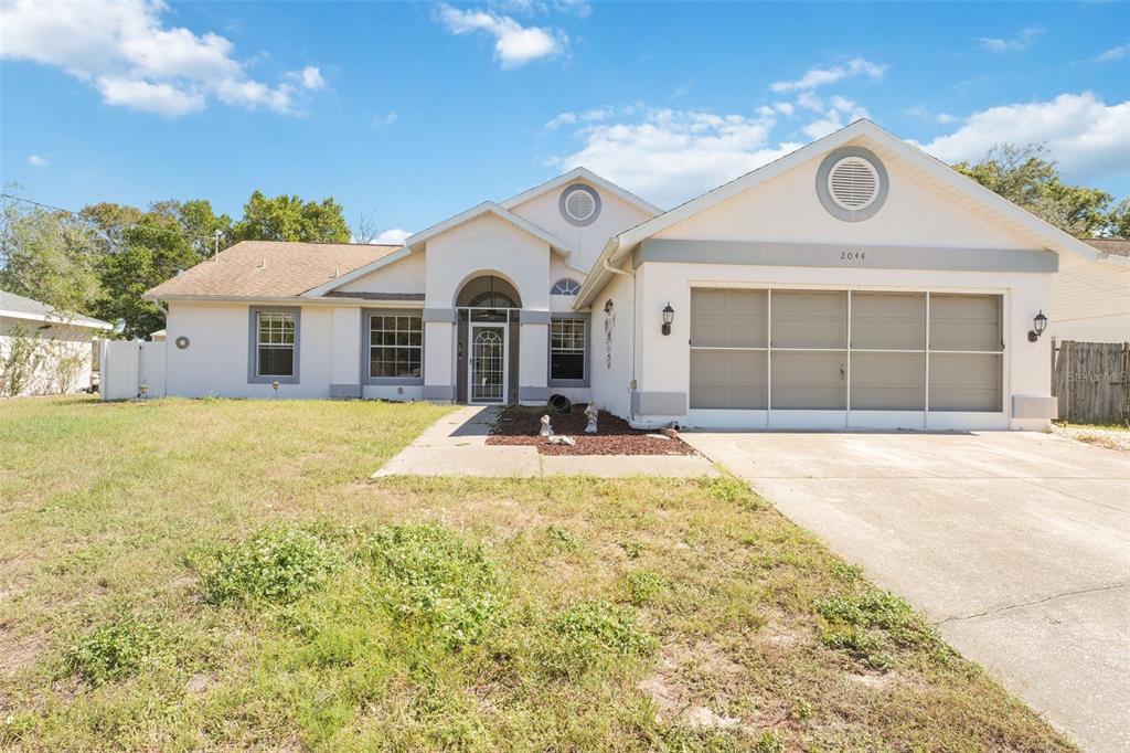 2044 Bishop Road Spring Hill, FL 34608 - Photo 1 of 1 a front view of a house with a yard and garage