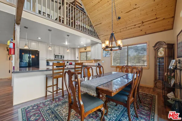 a kitchen with stainless steel appliances granite countertop a refrigerator a stove top oven and a dining table with wooden floor