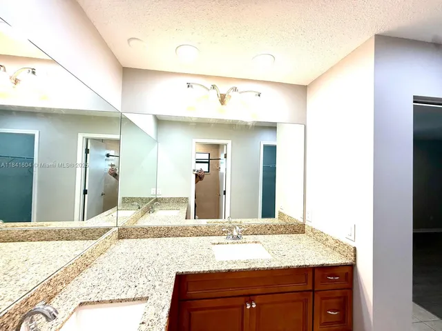 a bathroom with a granite countertop sink and a mirror