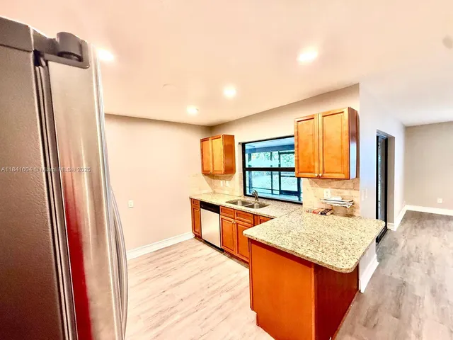 a kitchen with stainless steel appliances granite countertop sink refrigerator and window