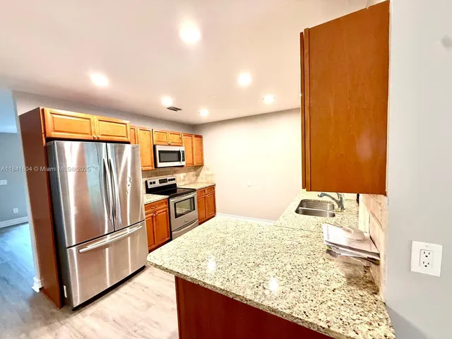 a view of a kitchen with furniture a ceiling fan and wooden floor