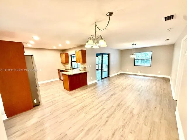 a view of a hallway with wooden floor and a refrigerator