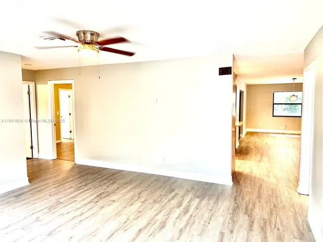a view of an empty room with a window and a ceiling fan