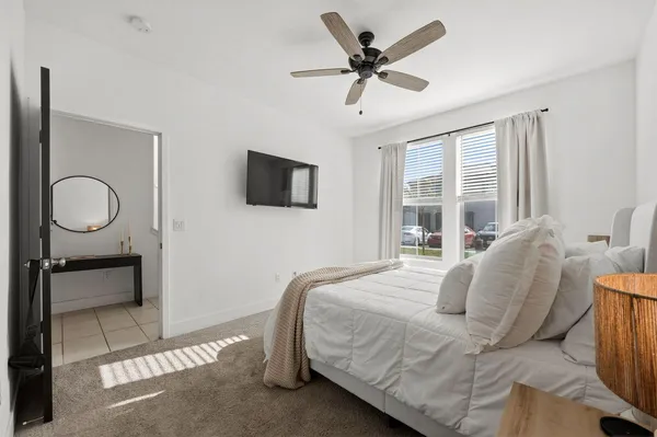 a bedroom with a bed a dresser and flat screen tv