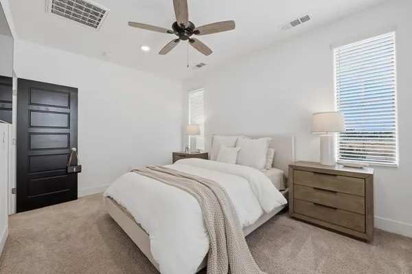 a bedroom with a bed a dresser and a chandelier