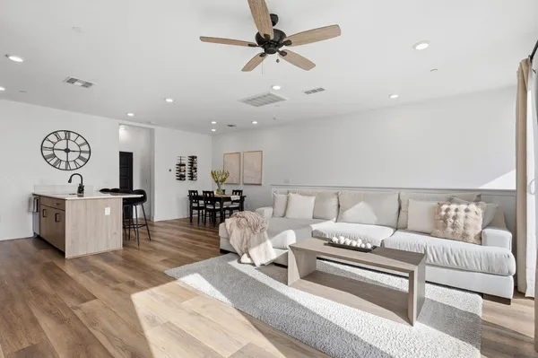 a living room with furniture a clock and a ceiling fan