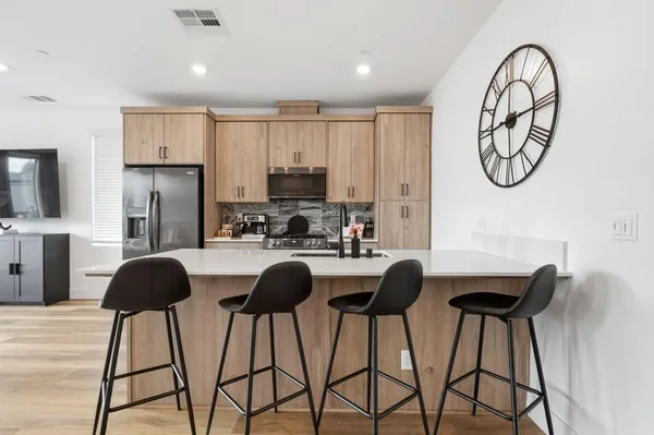 a kitchen with stainless steel appliances granite countertop a dining table chairs and a refrigerator