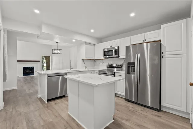 a kitchen with kitchen island a refrigerator stove and sink